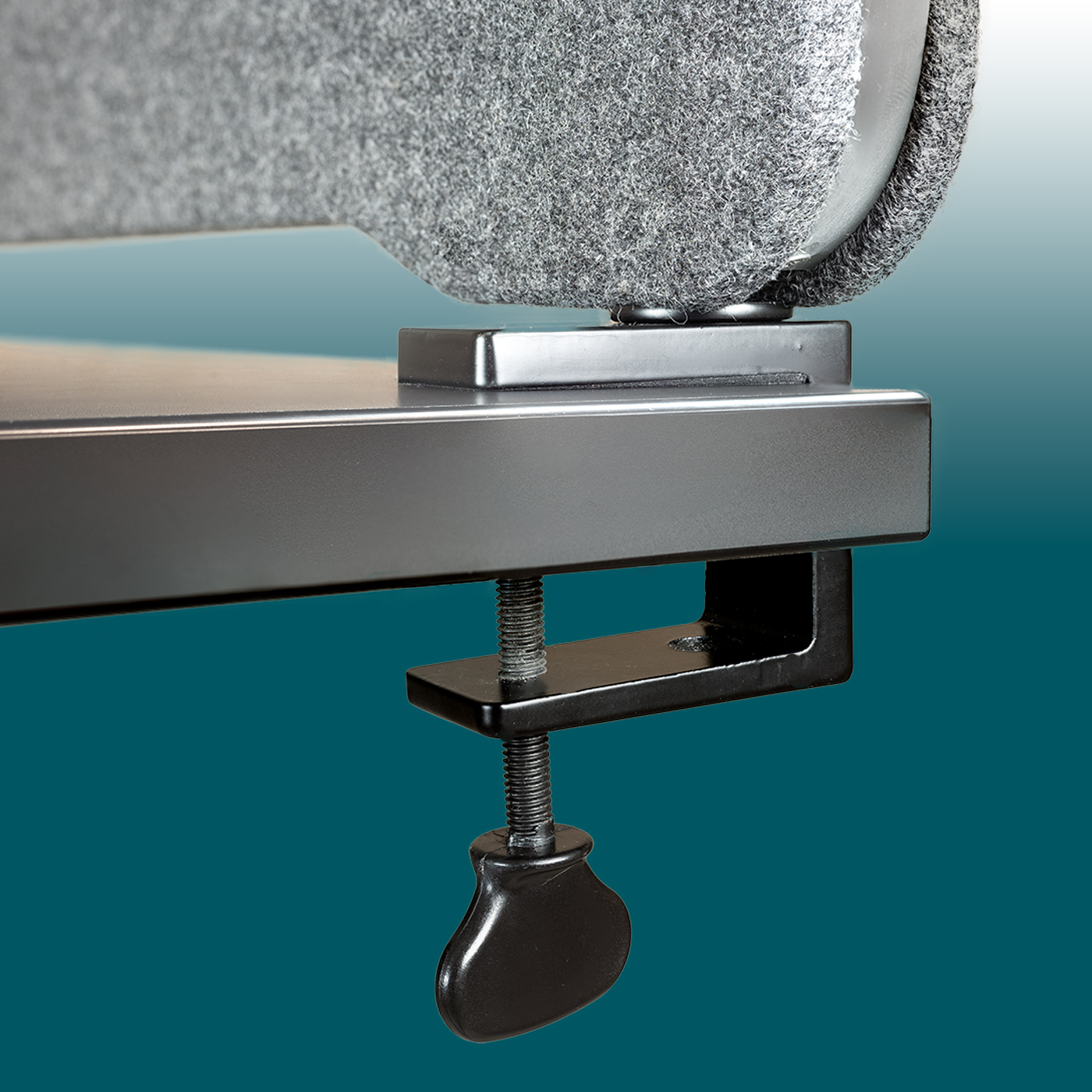 Close-up of a grey acoustic table partition with a black screw clamp attached to the table. Dark grey metal bracket, non-slip rotary knob. Felt fabric with a rounded edge and rubber trim visible.
