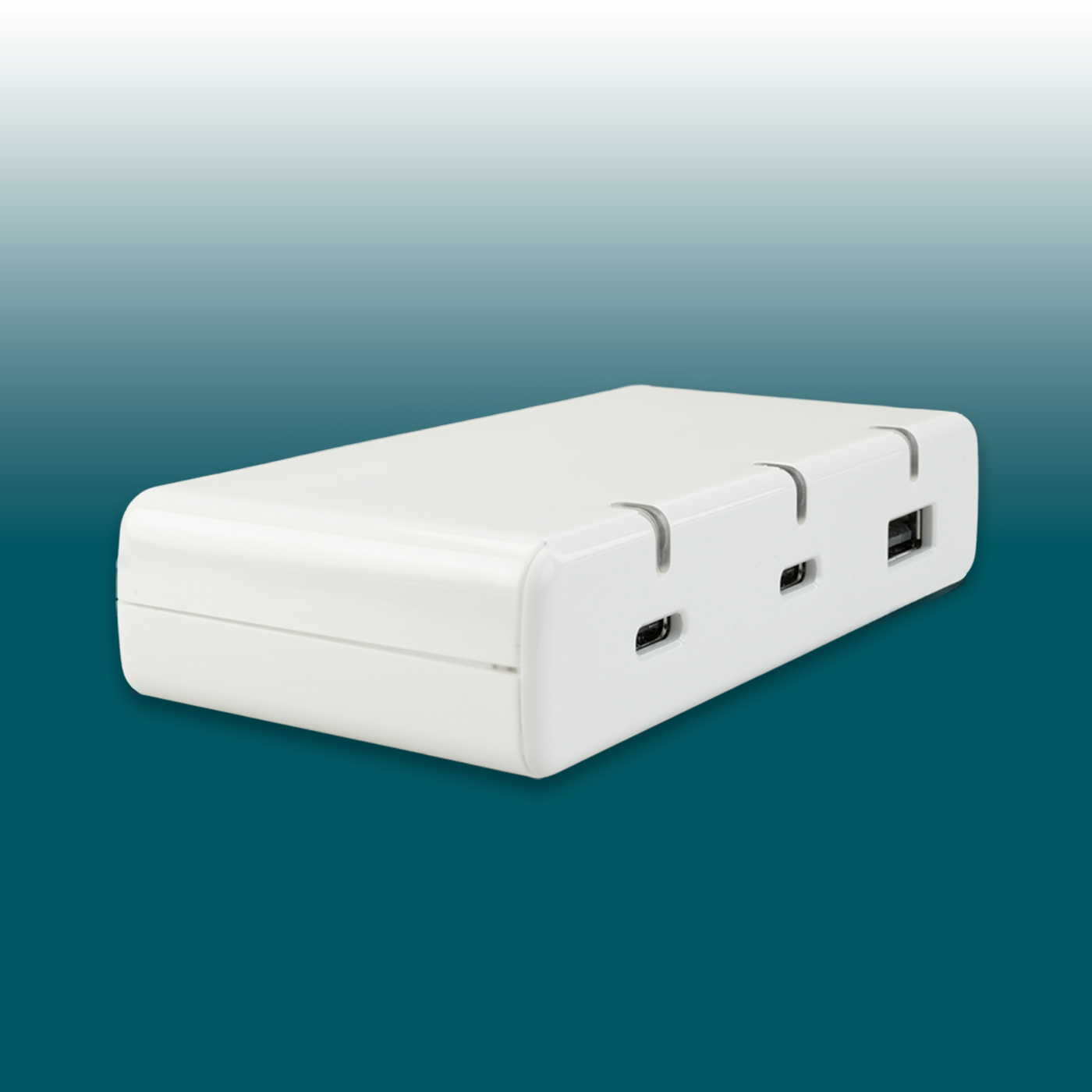 A slim, white USB charger, rectangular with rounded corners, rests at an angle on a turquoise-blue background. At the front are two USB-C ports and one USB-A port, ready to charge various devices. Desk2Device: compact and modern.