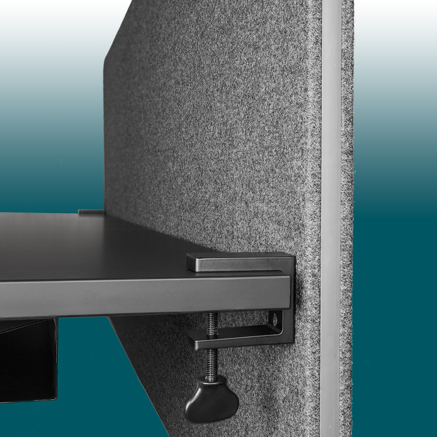 Close-up of a dark grey, felt-covered EDGE desk partition, securely attached to a desk top. A black metal arm with a screw clamp secures the sound-absorbing acoustic panel; a light-coloured, narrow rubber strip runs along the edge.